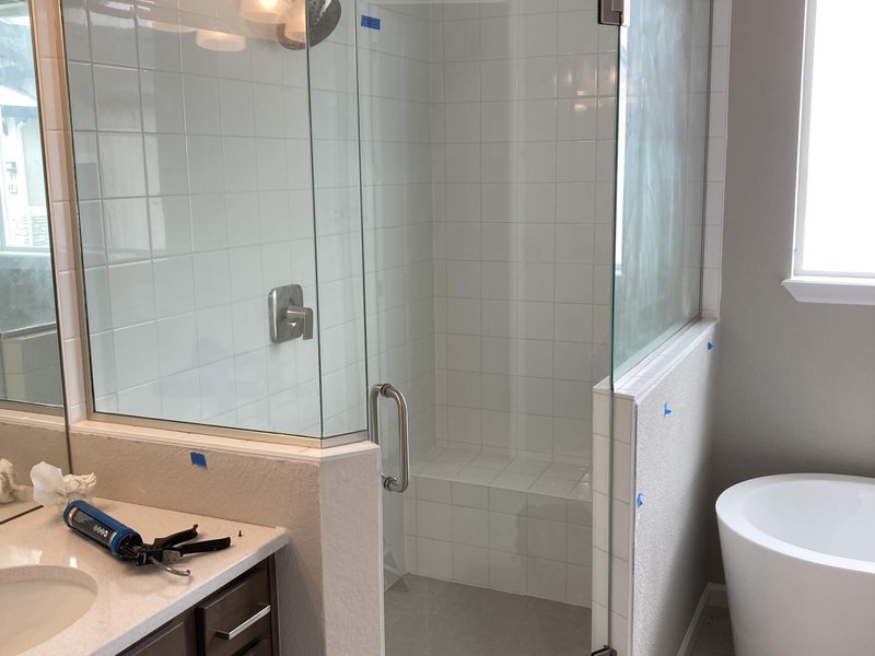 Frameless neo-angle shower enclosure with header and brushed nickel hardware