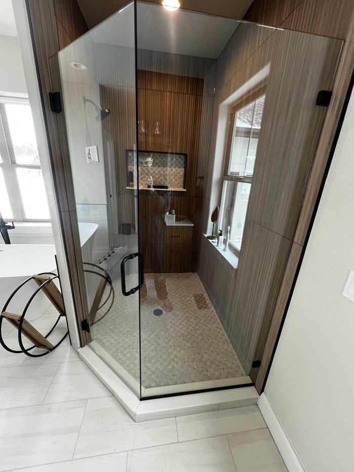 Frameless specialty-layout shower with black hardware and wood-look tile