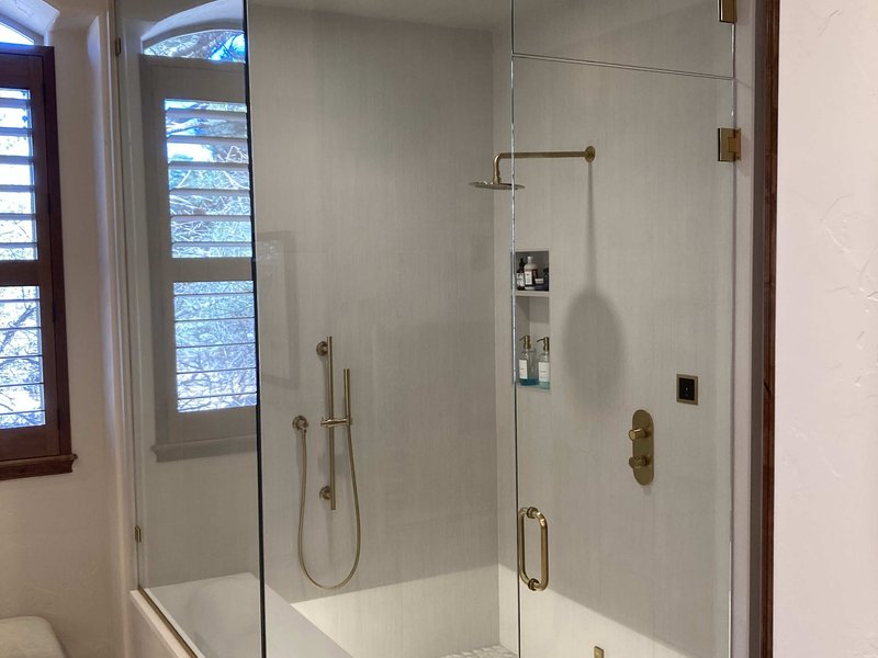 Frameless steam shower enclosure with satin brass gold hardware