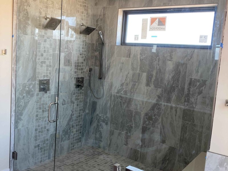 Frameless steam shower with chrome clips and gray marble tile