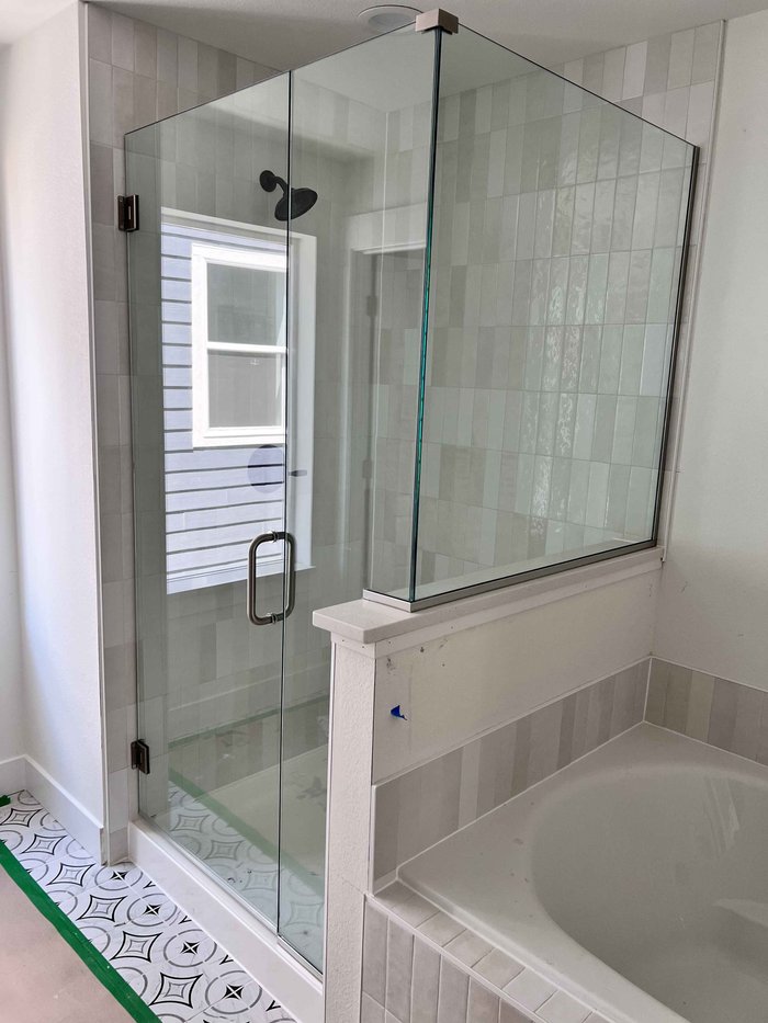 Frameless swing-door shower with brushed nickel hardware, U-channel, and notched return panel