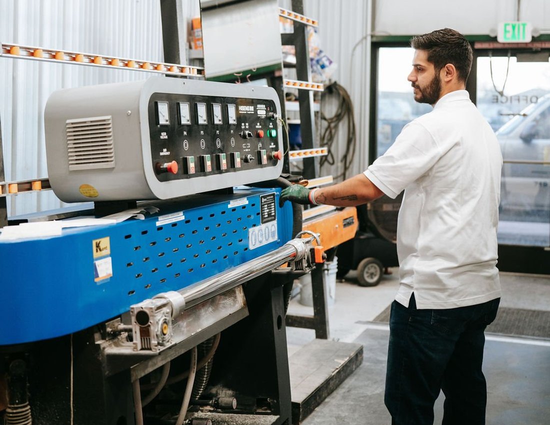 Kent Glass technician operating a glass fabrication machine in the Colorado Springs shop